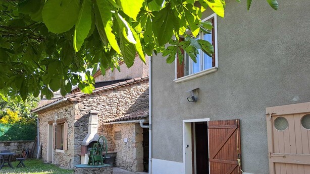 A stone building with a wooden door and a window, a white plastic chair, and a small garden area. - Les Bons Enfants - VENES (VENES)