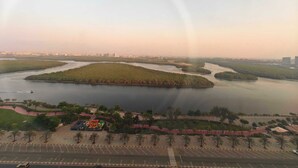 Une vue aérienne d’une zone côtière avec une étendue d’eau importante, des îles verdoyantes et un parking équipé d’une aire de jeux.