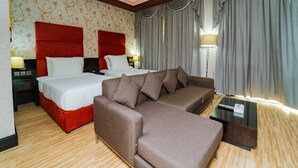 Une chambre d’hôtel avec deux lits, un canapé, une table de chevet et une lampe.