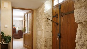 A stone wall with a wooden door and a glass door leading to a living area with a sofa and a lamp. - Saint Martial - Terre de Bancalié (Terre de Bancalié)