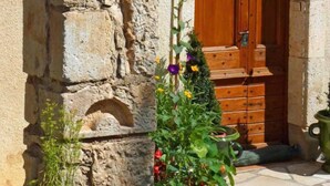 A stone wall with a small statue niche, a wooden door, and potted plants. - Saint Martial - Terre de Bancalié (Terre de Bancalié)