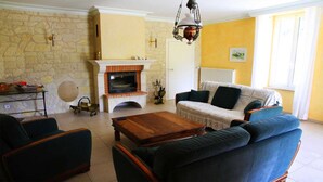 Un salon avec un mur en pierre, une cheminée, un canapé et une table basse.