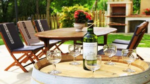 Une table en bois, avec une bouteille de vin et des verres, posée sur un tonneau.