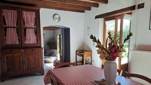 A dining area with a checkered tablecloth, wooden cabinets, a clock, and a vase with flowers. - La Teulière - LOMBERS - Gîte (LOMBERS)
