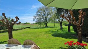 An outdoor seating area with a table, chairs, and a large umbrella. - La Teulière - LOMBERS - Gîte (LOMBERS)