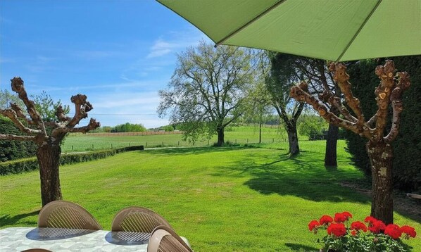 Un área de estar al aire libre con una mesa, sillas y un paraguas grande.