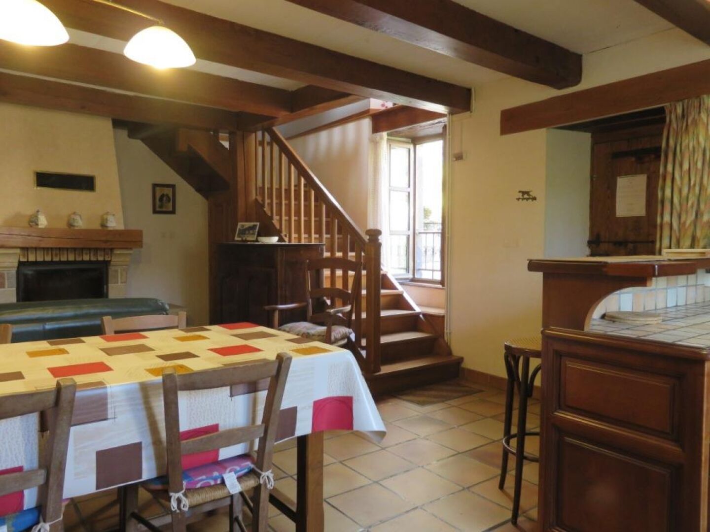 Un coin repas chaleureux avec une table et des chaises en bois, une cheminée et un escalier menant à une autre pièce.
