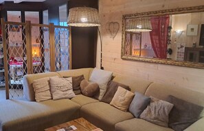 A cozy living room with a sectional sofa, two hanging wicker lamps, and a large mirror on the wall.