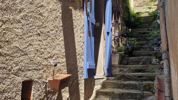 Una estrecha escalera de piedra en un pueblo histórico, con contraventanas de madera en los edificios.