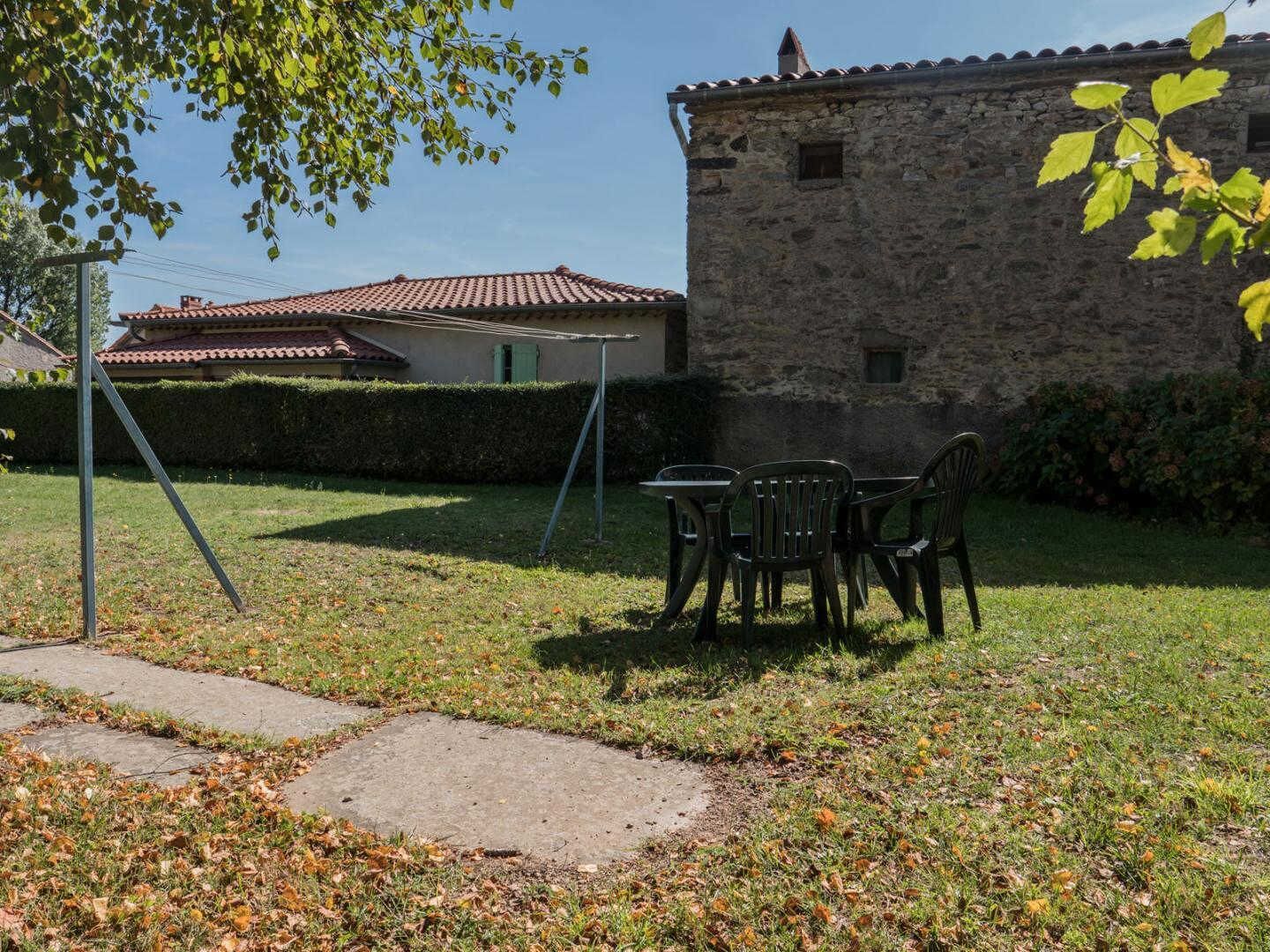 A stone building with a tiled roof, a grassy yard, and a swing set.