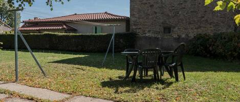 A stone building with a tiled roof, a grassy yard, and a swing set.