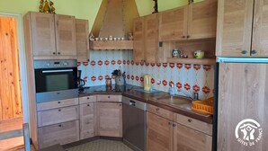A compact kitchen with wooden cabinets, a built-in oven, and a tiled backsplash. - Les Barreaux - MONTVALEN (MONTVALEN)