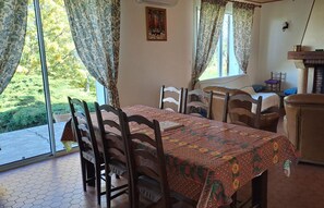 Un comedor con una mesa dispuesta para cuatro personas, sillas de madera y un mantel estampado.