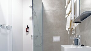 A modern bathroom with a glass shower enclosure, a white toilet, and a white sink with a mirror. - The Vlasta Collection Rooms (Zagreb)