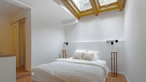 A bedroom with a skylight, a bed, bedside tables, and a wooden floor. - The Vlasta Collection Rooms (Zagreb)