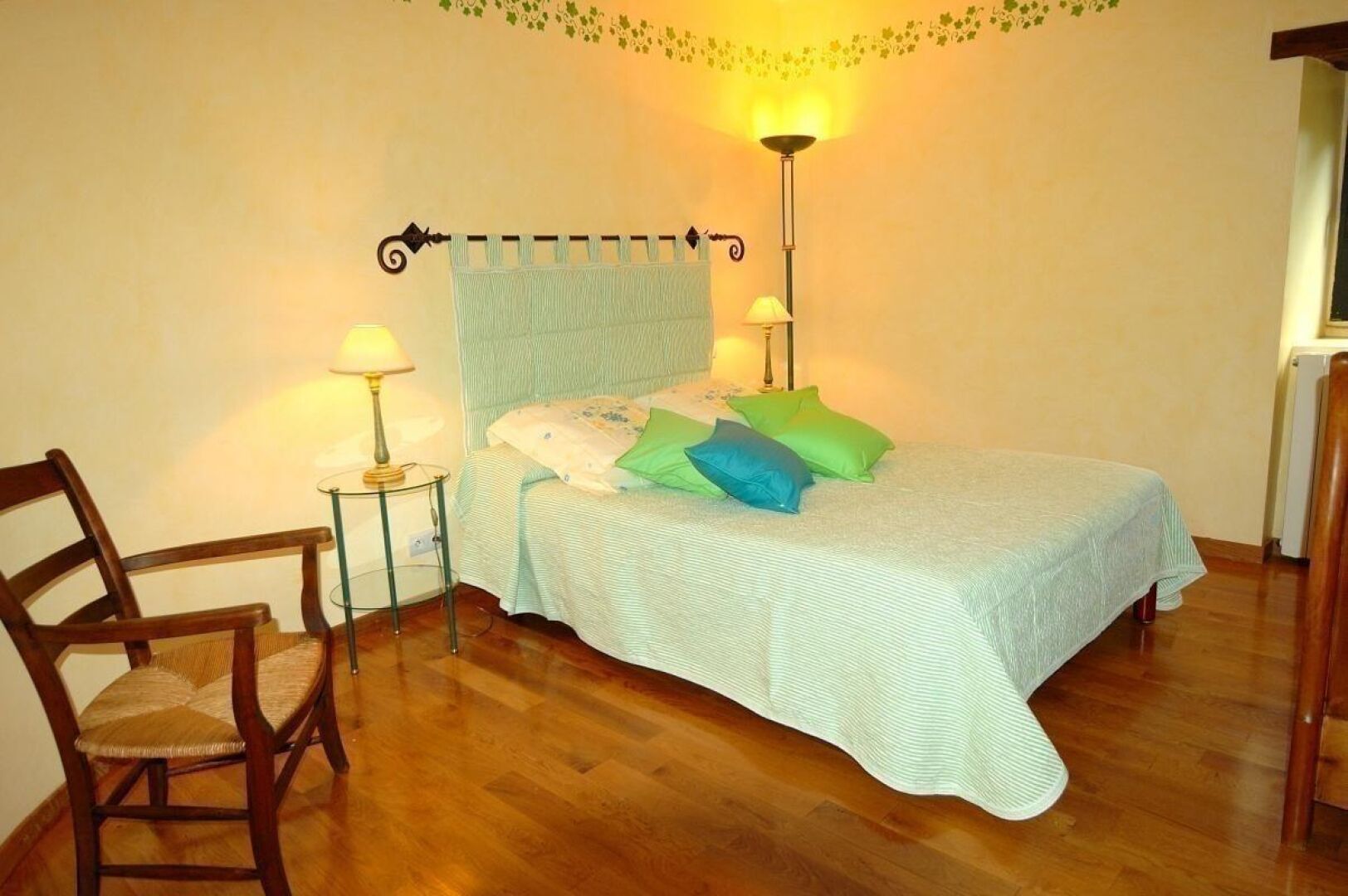A bedroom with a bed, a chair, two bedside lamps, and a wall-mounted light fixture.
