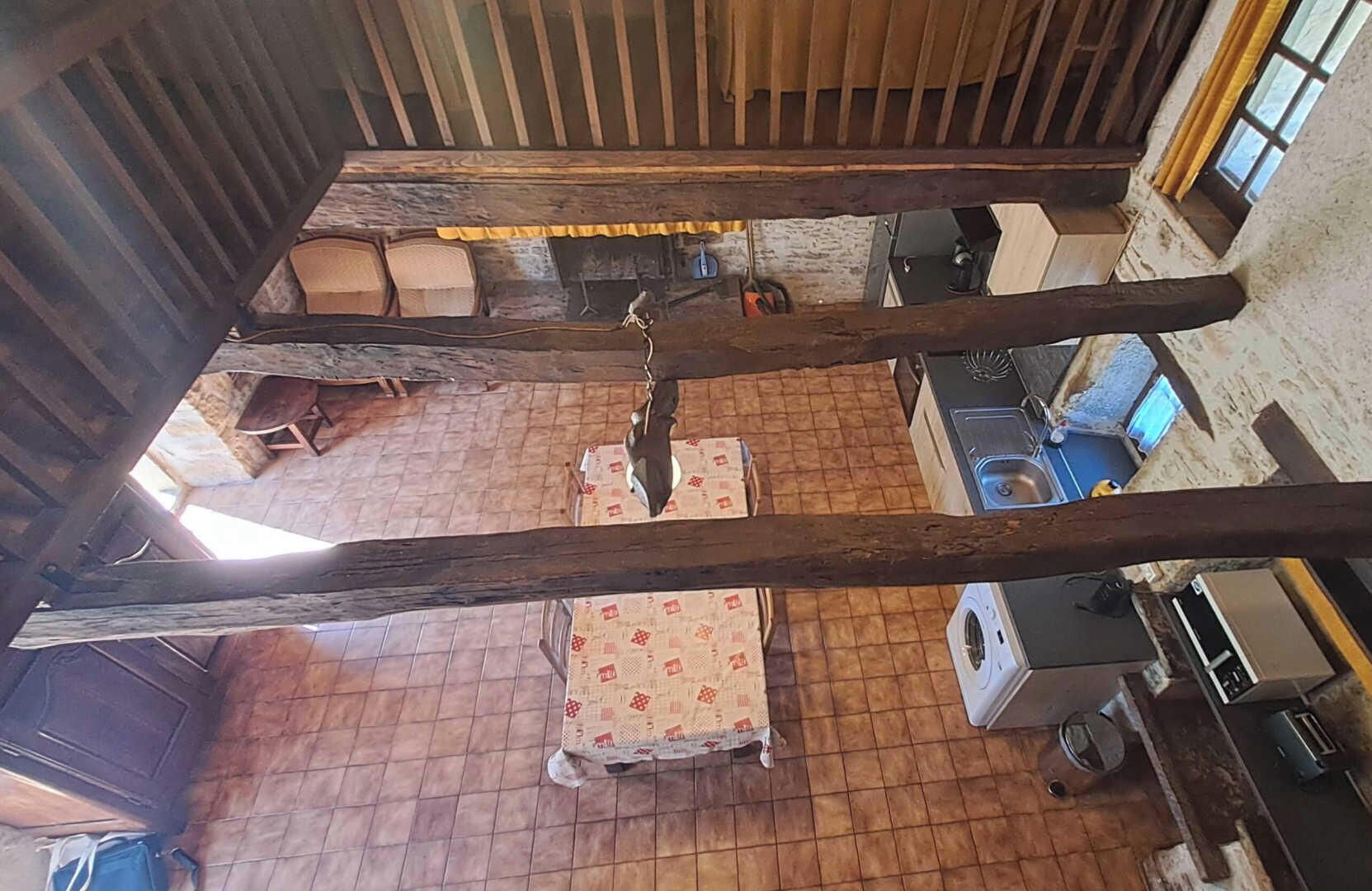 Ein rustikales Zimmer mit Holzbalkendecke, Fliesenboden, Waschmaschine und Spüle.