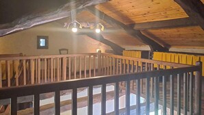 A rustic wooden interior with a balcony, wooden beams, and a hanging light fixture.
