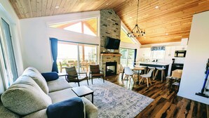 A spacious living area with a sofa, chairs, a fireplace, and a kitchen in the background.