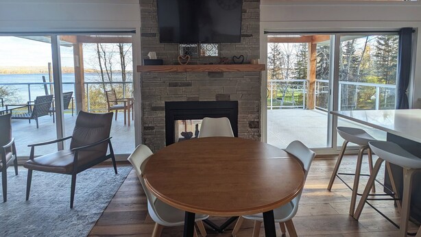 A modern interior with a stone fireplace, a large round table, and a TV mounted on a stone wall.