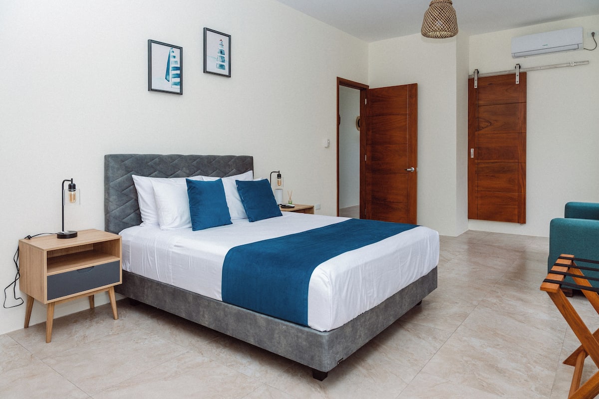 A bedroom with a bed, bedside tables, a wardrobe, and a hanging light fixture.