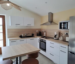 A modern kitchen with white cabinets, a stainless steel refrigerator, a microwave, and a coffee maker.