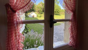 A door with two windows, each adorned with red and white checkered curtains.