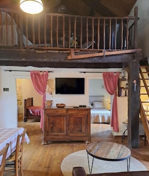 A rustic room with wooden furniture, a television, and a staircase.