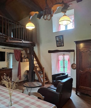 A rustic interior with a staircase, wooden furniture, and a dining area.