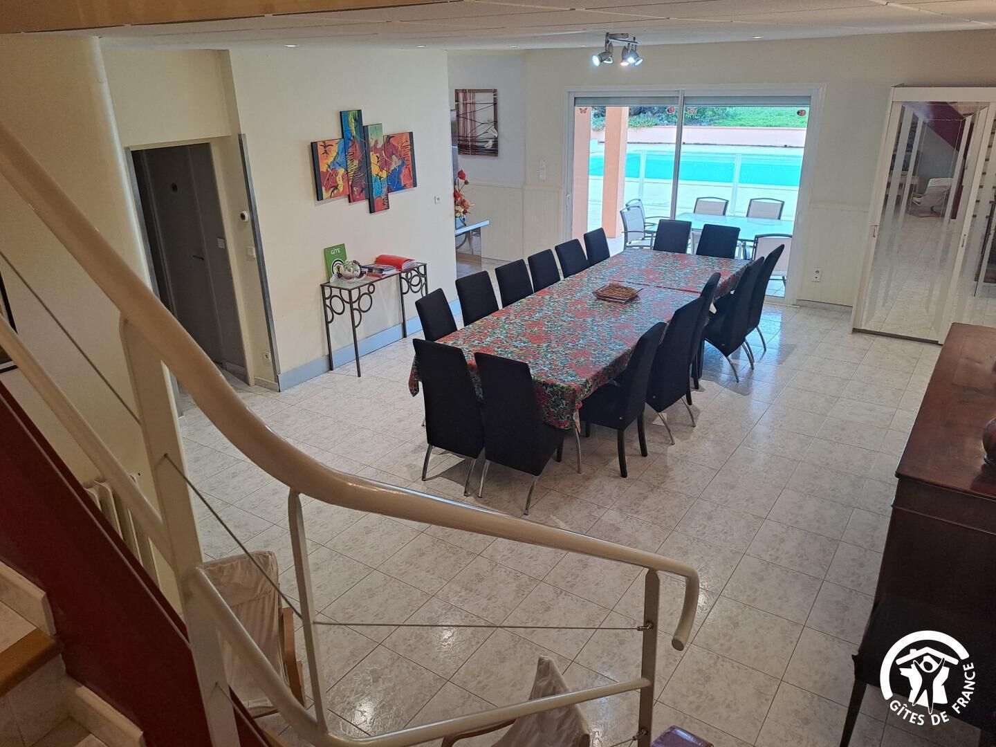 Un espace repas comprenant une longue table, des chaises et un escalier menant à une autre pièce.