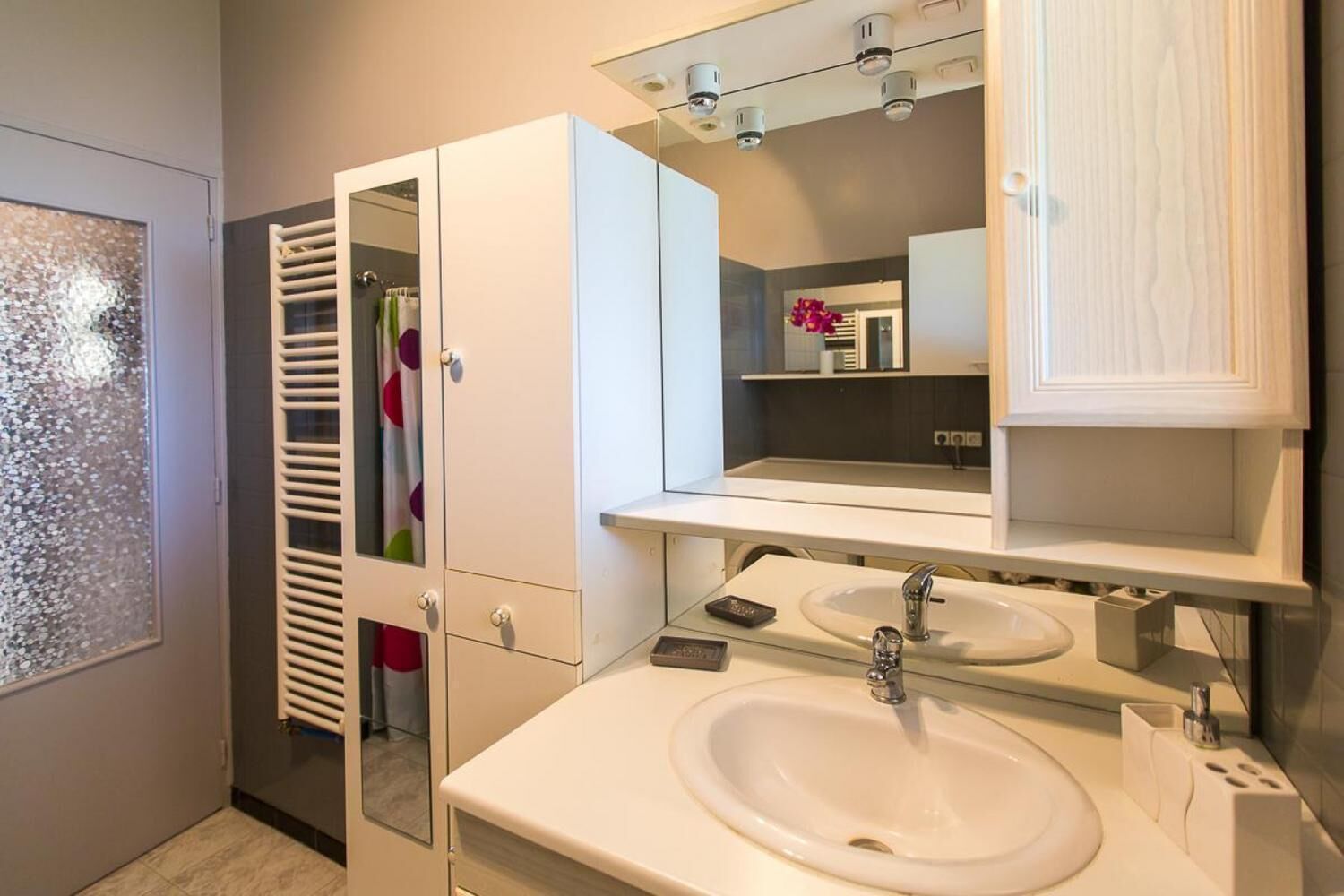 A modern bathroom with a glass shower enclosure, a white sink, and a mirror above the sink.