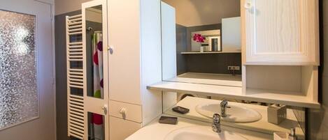 A modern bathroom with a glass shower enclosure, a white sink, and a mirror above the sink.