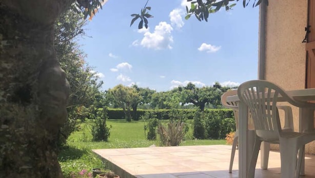 A patio with a view of a lush garden and a clear sky.