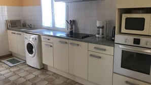 A compact kitchen with a washing machine, microwave, and oven.