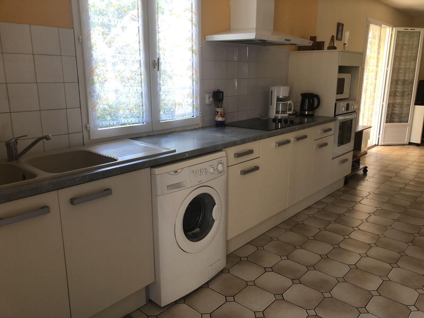 Une cuisine compacte équipée d’un lave-linge intégré, d’une machine à café et d’un four à micro-ondes.