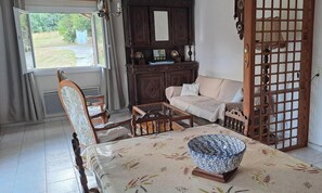 Una habitación con una mesa de comedor, sillas, un sofá, un armario y vistas al exterior.