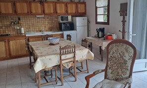 Una cocina con armarios de madera, una mesa de comedor con sillas, un microondas y un refrigerador.