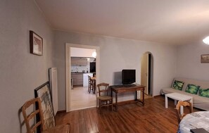 Un espacio habitable compacto con kitchenette, comedor y zona de estar con sofá y sillas.