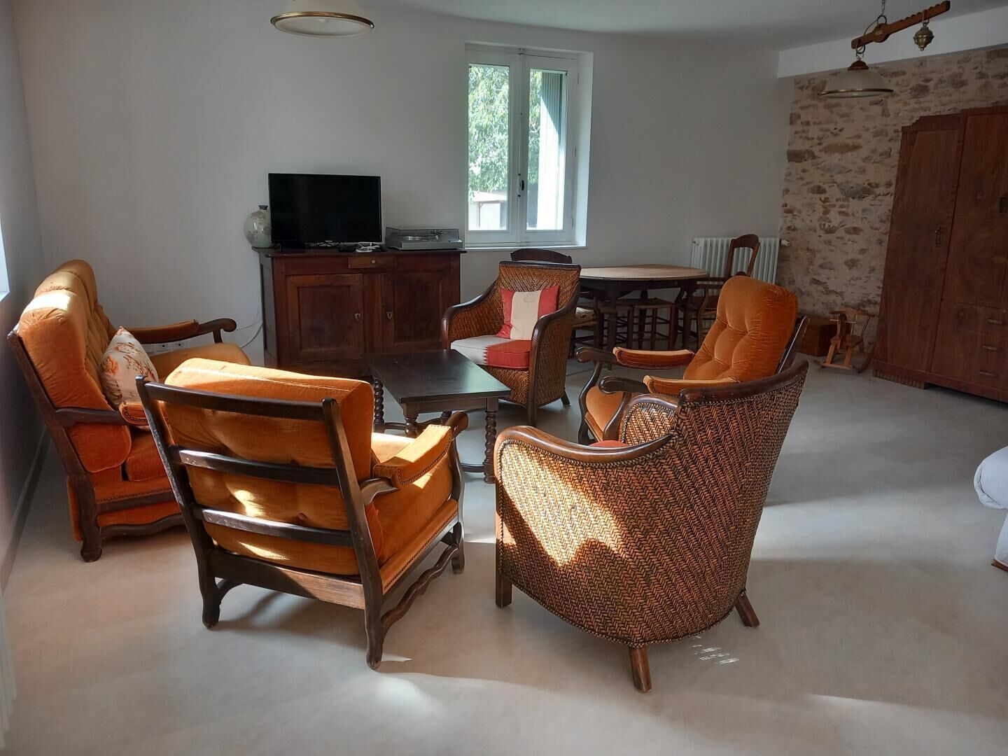 Un salon comprenant un téléviseur, une table à manger et plusieurs chaises.
