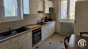 Een compacte keuken met witte kasten, een magnetron, een koffiezetapparaat en een houten aanrecht.