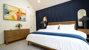 Een slaapkamer met een bed, een dressoir, een spiegel en een schilderij aan de muur.