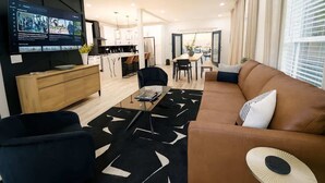 Een moderne woonkamer met een bank, een salontafel en een aan de muur bevestigde televisie.