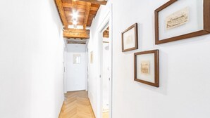 A hallway with wooden flooring, white walls, and framed artwork.