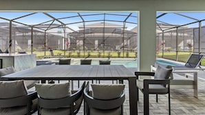 An outdoor patio with a table and chairs, a pool, and a view of a residential area.