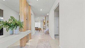 A modern hallway with a wooden accent wall, a white bench, and a potted plant.