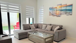 Ein modernes Wohnzimmer mit einem Ecksofa, einem Glastisch und einem roten Sessel.