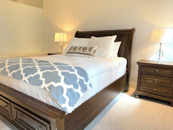 A neatly made bed with a patterned bedspread, a wooden headboard, and two bedside lamps.