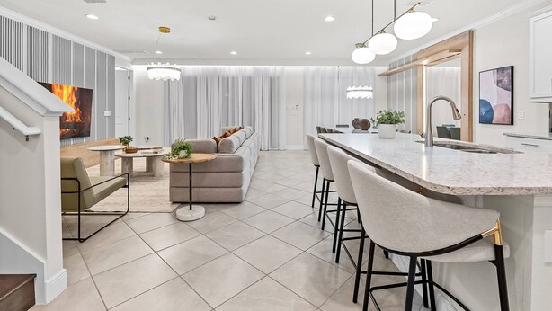 A modern kitchen with a central island, bar stools, and a dining area with a sofa and coffee table.