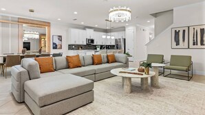 A modern living room with a sectional sofa, a round coffee table, and a dining area with chairs.