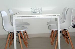 A white table with four chairs, each with wooden legs, and a clear glass basket on the table. - Twin Sands Private Apartment, Phuket (Patong)